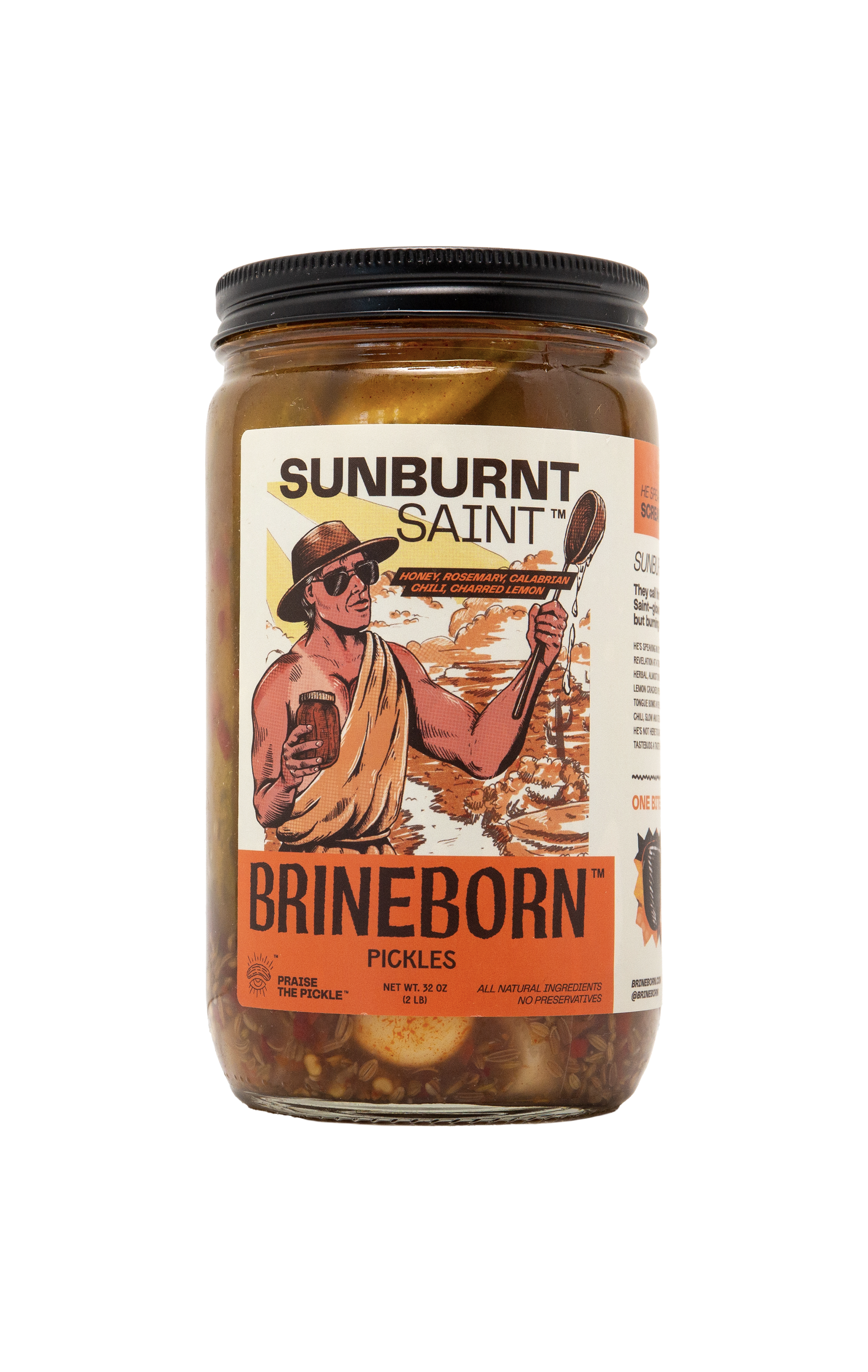 Glass jar of Brineborn Sunburnt Saint pickles with an orange and white front label showing an illustrated person holding a jar and a feather near a sunset scene.